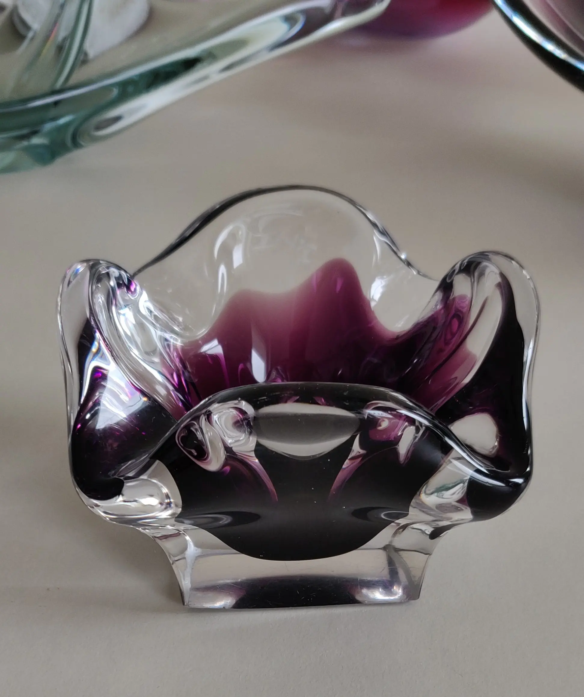 Breite/Länge: 11x11cm<br />Höhe: 8cm<br />Gewicht: 770g<br /><br />Mundgeblasener Murano Glas Aschenbecher<br />Klares Glas mit blauen Innenfang<br />Plangeschliffener Boden mit Schiebespuren und einseitig rauer Schleifkante<br />Keine Chips<br />kleine Lufteinschlüssse im Glas<br />Gerippter Körper mit wellenförmig gestaltetem Rand und 4  ca. 15-18mm großen Zigarrenablagen